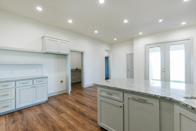 kitchen featuring light stone counters, backsplash, recessed lighting, french doors, and dark wood-style flooring