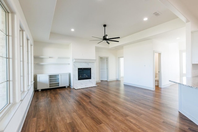 unfurnished living room with a premium fireplace, ceiling fan, and dark hardwood / wood-style flooring