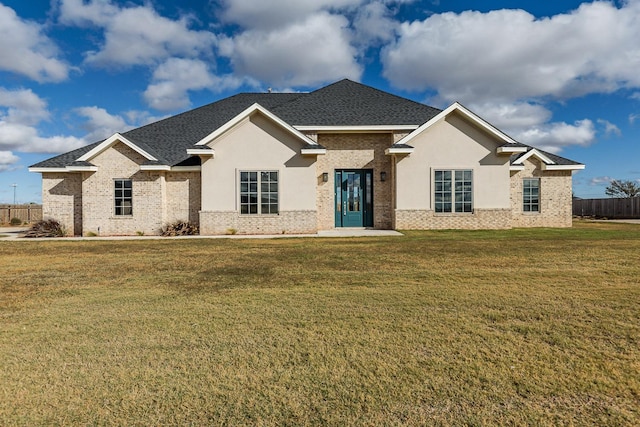 ranch-style house with a front yard, fence, brick siding, and a shingled roof