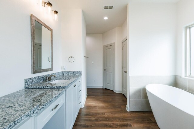 bathroom with hardwood / wood-style flooring, vanity, and a tub