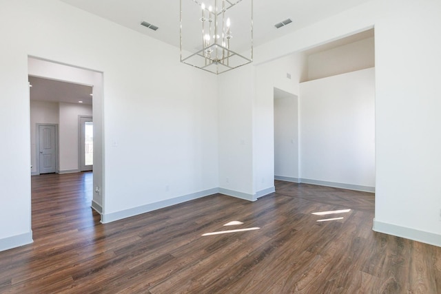 unfurnished room featuring dark wood finished floors, a notable chandelier, baseboards, and visible vents