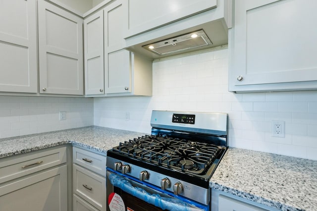 kitchen with gas stove, tasteful backsplash, extractor fan, and light stone counters