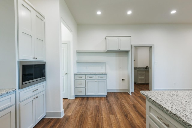 kitchen featuring dark wood finished floors, light stone counters, recessed lighting, and built in microwave