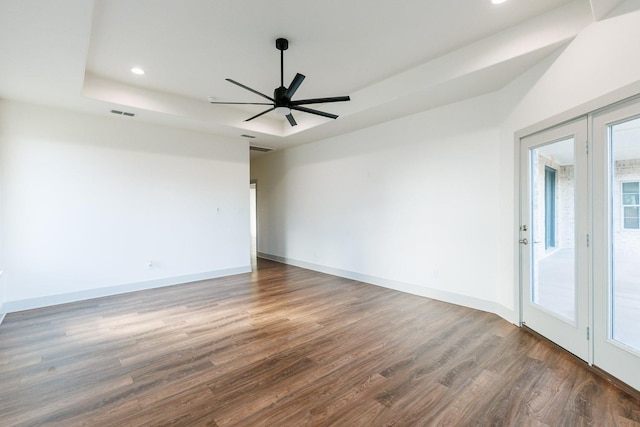 empty room featuring hardwood / wood-style floors, a tray ceiling, french doors, and ceiling fan