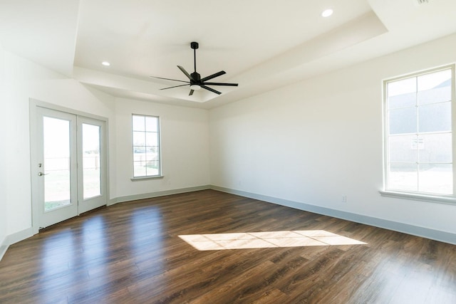 empty room with recessed lighting, baseboards, a tray ceiling, and dark wood-style flooring