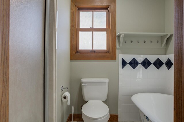 bathroom with toilet and tile walls