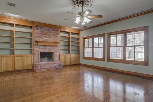 unfurnished living room with hardwood / wood-style flooring, ceiling fan, ornamental molding, and a fireplace