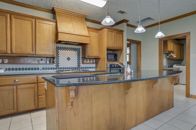 kitchen with black microwave, a breakfast bar, and an island with sink