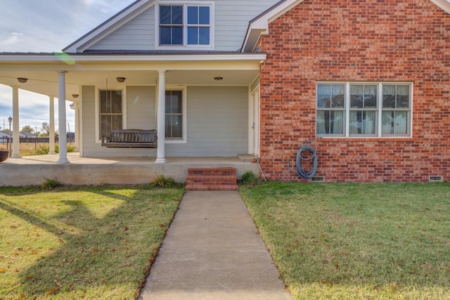 property entrance with covered porch and a lawn