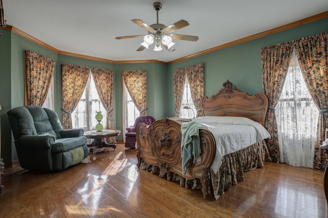 bedroom with multiple windows, wood-type flooring, ceiling fan, and crown molding