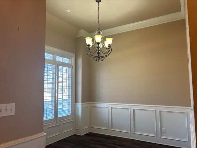 unfurnished dining area featuring ornamental molding, dark hardwood / wood-style floors, and a notable chandelier