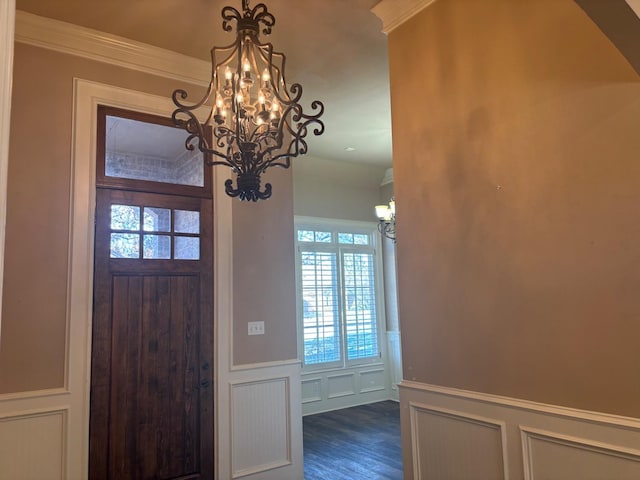 foyer entrance with crown molding, an inviting chandelier, and dark hardwood / wood-style flooring