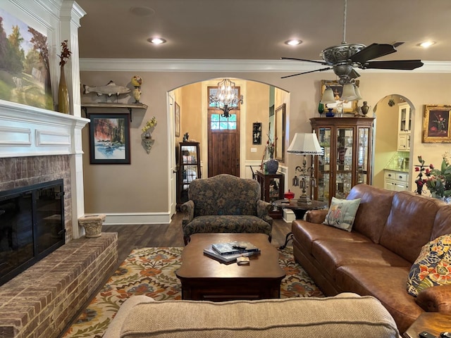 living room with dark hardwood / wood-style flooring, a brick fireplace, ornamental molding, and ceiling fan