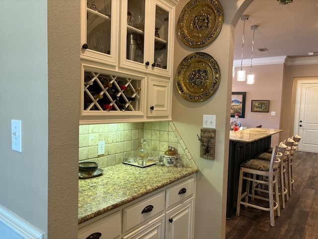 bar with white cabinetry, crown molding, dark hardwood / wood-style flooring, and backsplash