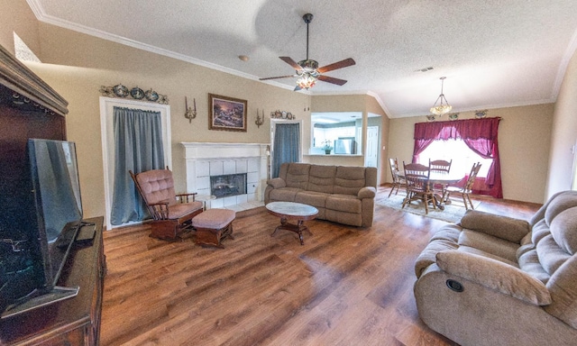 living room with a tiled fireplace, hardwood / wood-style floors, crown molding, and a textured ceiling