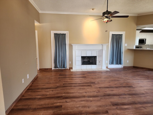 unfurnished living room with a textured ceiling, a tile fireplace, wood finished floors, a ceiling fan, and crown molding