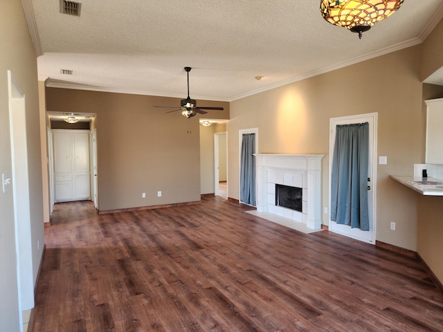 unfurnished living room with dark wood finished floors, crown molding, visible vents, a ceiling fan, and a tile fireplace