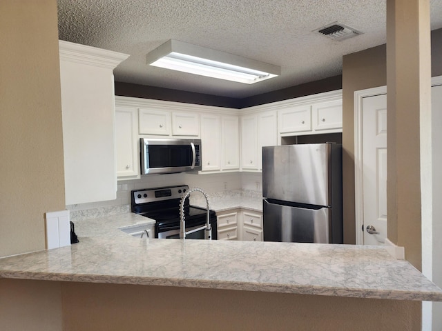 kitchen with stainless steel appliances, a peninsula, light countertops, and visible vents