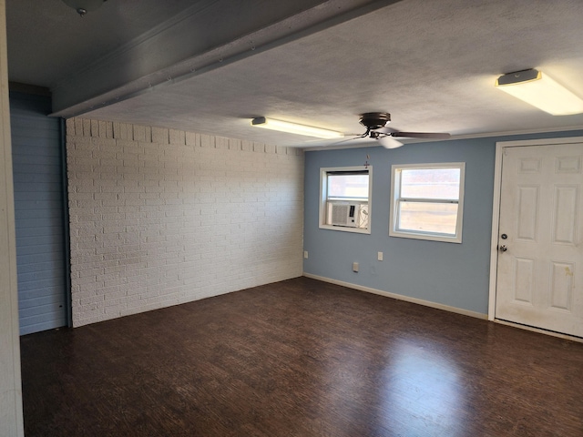 spare room featuring baseboards, brick wall, wood finished floors, cooling unit, and a textured ceiling