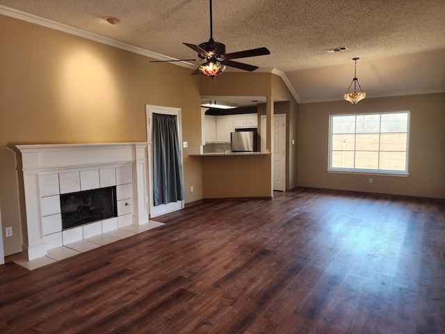 unfurnished living room featuring visible vents, ornamental molding, dark wood-style flooring, vaulted ceiling, and a fireplace