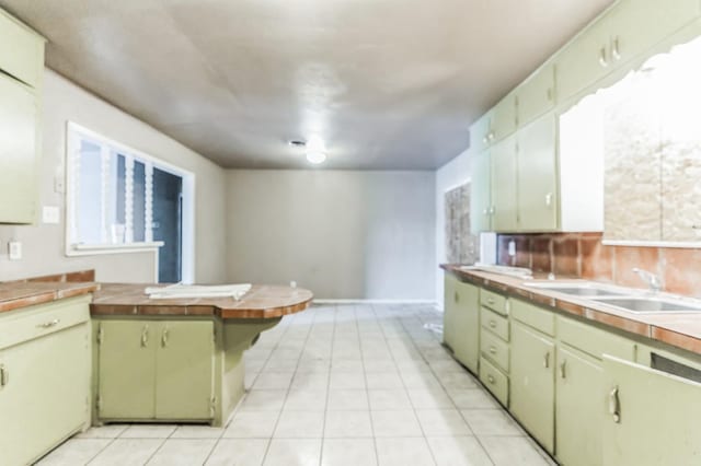 kitchen with tasteful backsplash, sink, light tile patterned floors, and wood counters