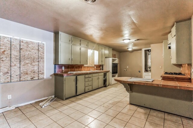 kitchen featuring tile countertops, light tile patterned floors, and black appliances