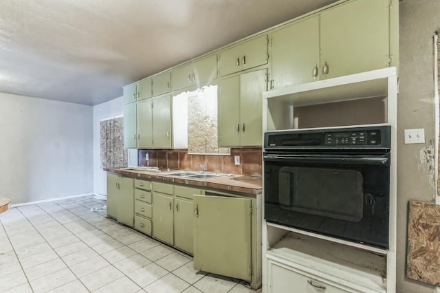 kitchen with backsplash, sink, oven, and light tile patterned floors