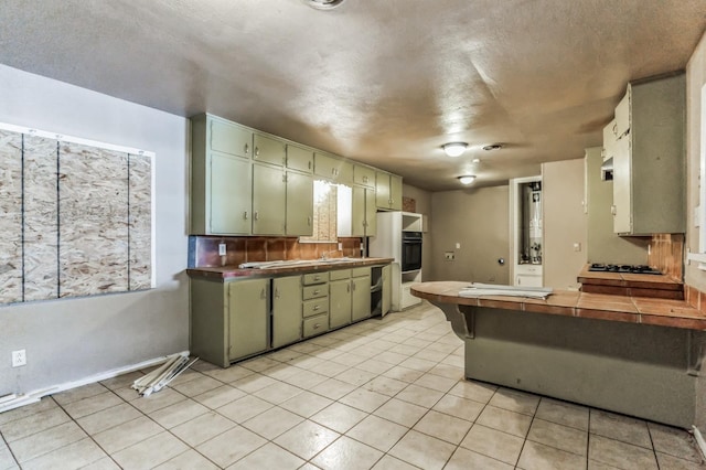 kitchen with black appliances, light tile patterned floors, decorative backsplash, and green cabinetry