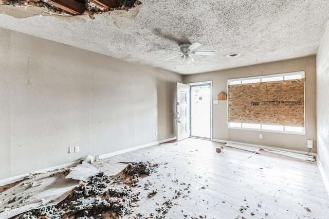 unfurnished room with ceiling fan and a textured ceiling