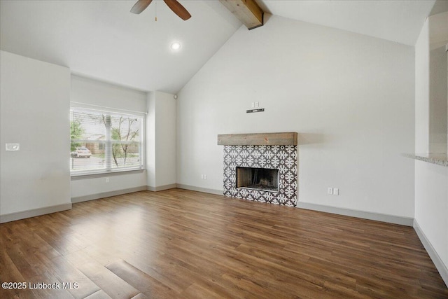10330 Ave X Ave, Lubbock, TX 79423 - unfurnished living room with a ceiling fan, beamed ceiling, a tiled fireplace, wood finished floors, and high vaulted ceiling