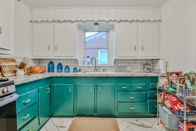 kitchen with white cabinetry, sink, stainless steel stove, and backsplash