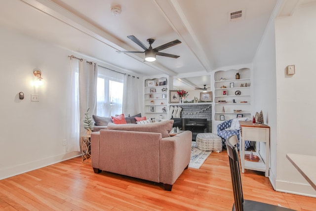 living room featuring a fireplace, wood-type flooring, beamed ceiling, and ceiling fan