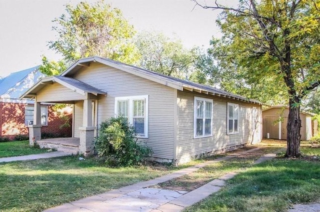 view of front of home with a storage shed, a front lawn, and a carport