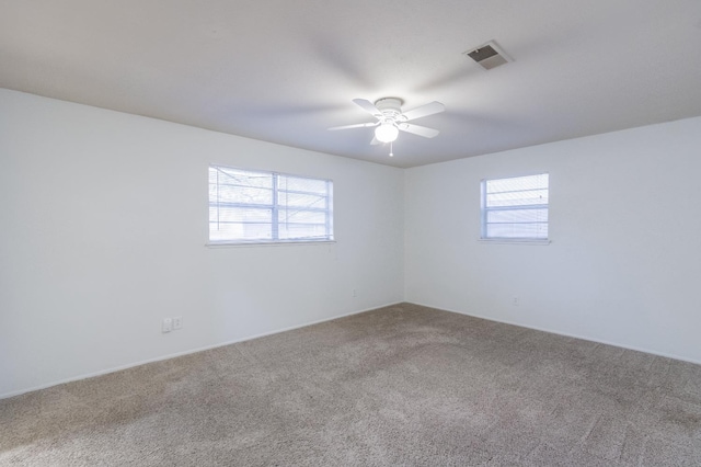 spare room with carpet, a healthy amount of sunlight, and ceiling fan