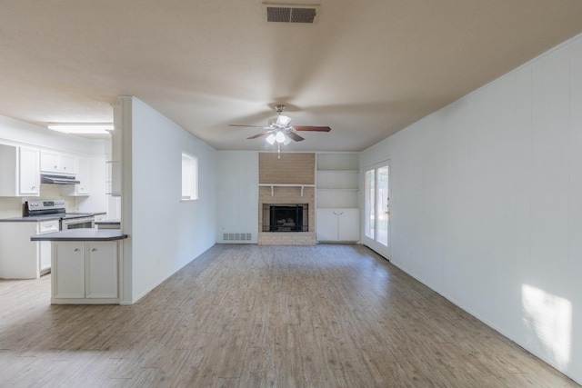 unfurnished living room featuring a brick fireplace, light hardwood / wood-style floors, and ceiling fan