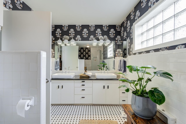 3003 19th St, Lubbock, TX 79410 - full bathroom with wallpapered walls, double vanity, tile walls, a shower stall, and wainscoting