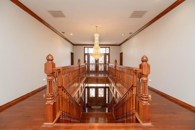 stairway with an inviting chandelier, hardwood / wood-style floors, and ornamental molding