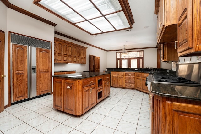 kitchen with stainless steel gas stove, hanging light fixtures, ornamental molding, a center island, and paneled built in fridge