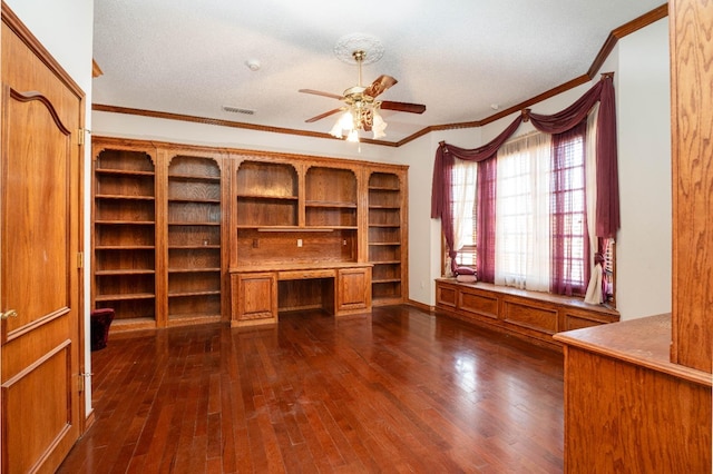 unfurnished office featuring ornamental molding, built in desk, ceiling fan, and dark hardwood / wood-style flooring