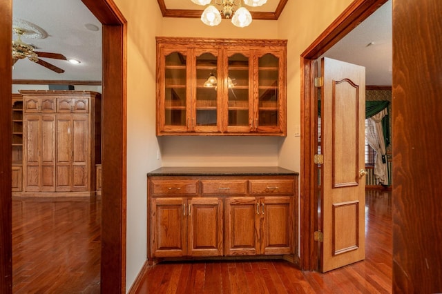 interior space featuring ornamental molding, dark hardwood / wood-style floors, and ceiling fan with notable chandelier