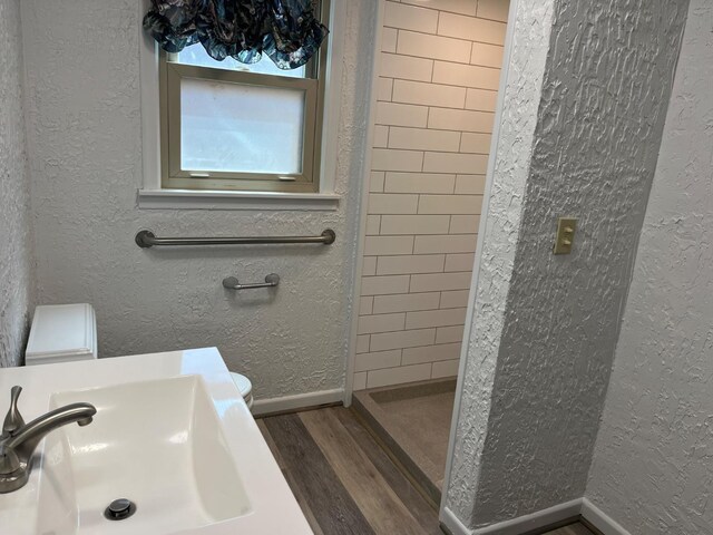 bathroom featuring tiled shower, sink, and hardwood / wood-style floors