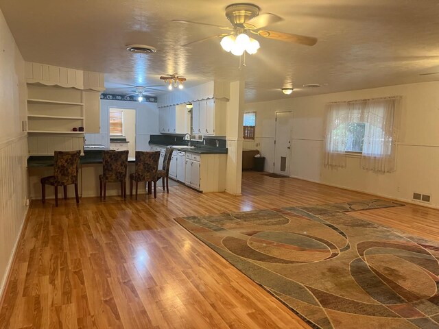 kitchen featuring white cabinetry, white dishwasher, sink, and light wood-type flooring