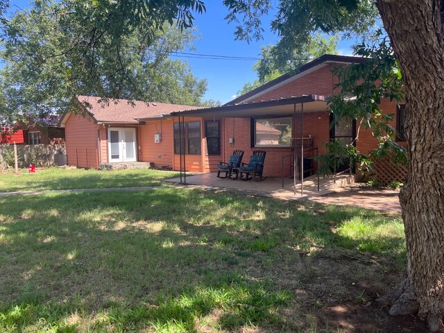 rear view of house with a patio and a yard