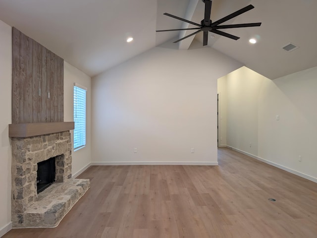 unfurnished living room featuring a stone fireplace, light hardwood / wood-style flooring, ceiling fan, and vaulted ceiling