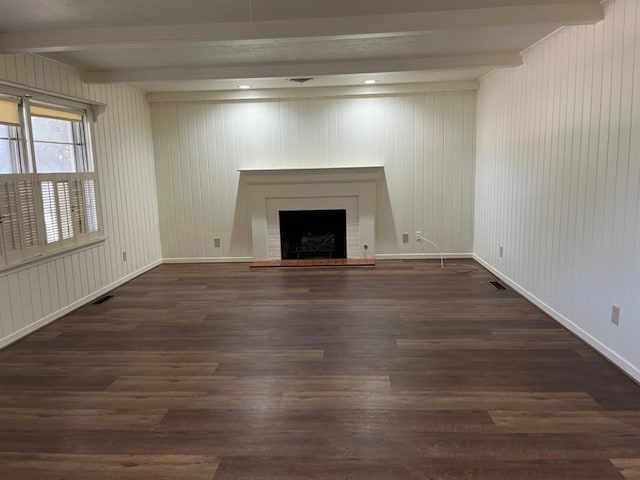 unfurnished living room featuring beamed ceiling, dark hardwood / wood-style floors, and wood walls