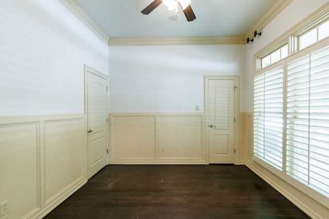empty room featuring dark wood-style floors, ornamental molding, a wainscoted wall, and a ceiling fan