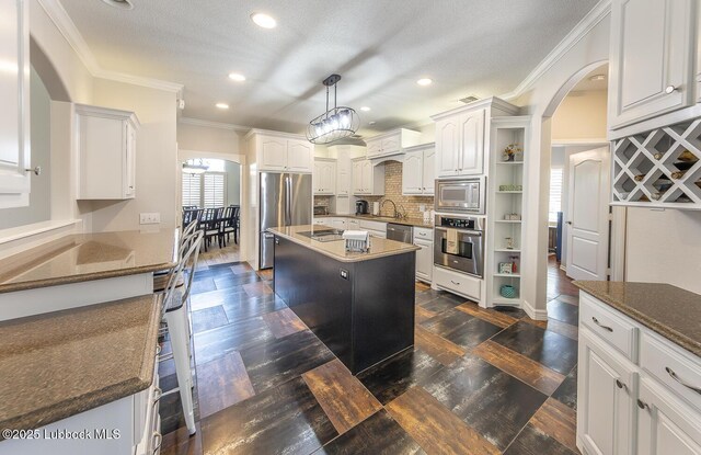 5004 County Rd 1430, Lubbock, TX 79407 - kitchen featuring stainless steel appliances, open shelves, arched walkways, crown molding, and white cabinets