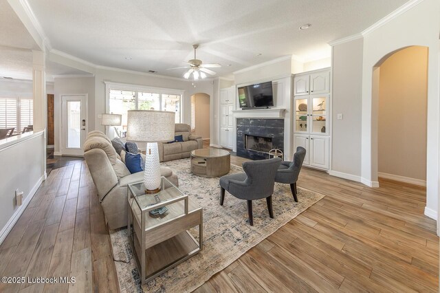 5004 County Rd 1430, Lubbock, TX 79407 - living room featuring arched walkways, ceiling fan, a premium fireplace, baseboards, and light wood-style flooring