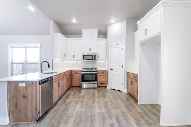 kitchen with sink, white cabinetry, light hardwood / wood-style flooring, stainless steel appliances, and decorative backsplash