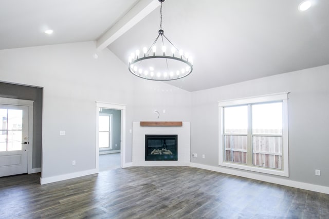 unfurnished living room with a notable chandelier, dark wood finished floors, baseboards, beamed ceiling, and a glass covered fireplace